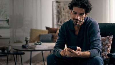 Hombre usando la app de electrodomésticos Siemens en su teléfono con un espacio de trabajo relajado